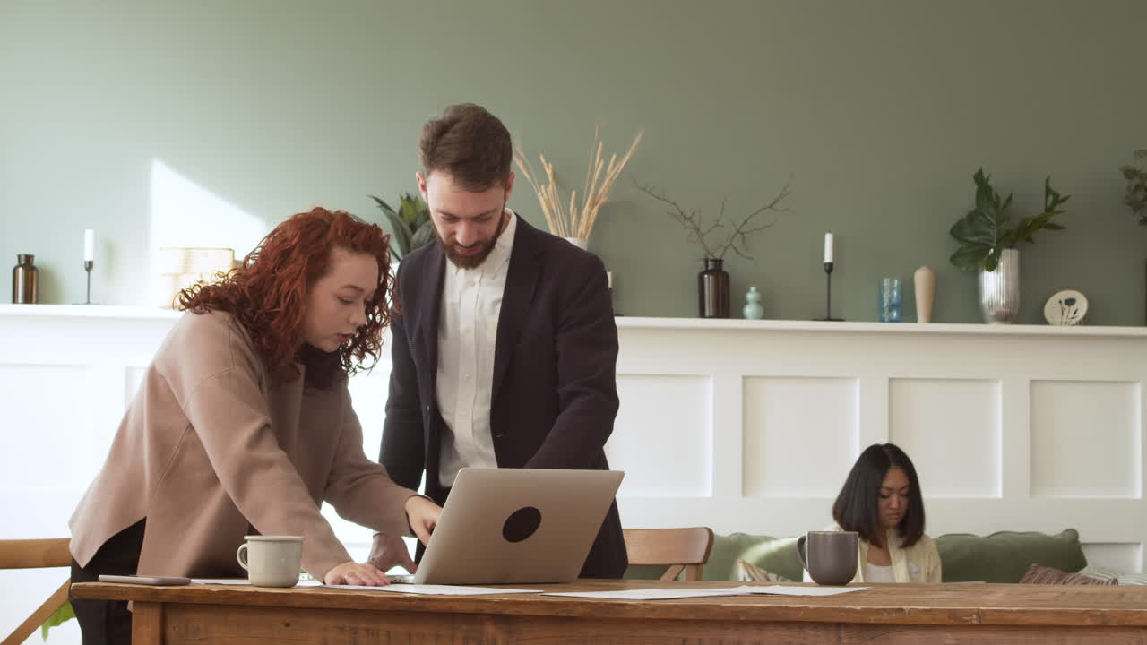 Woman And Man Standing At Table, Debating And Looking At Laptop Computer 1