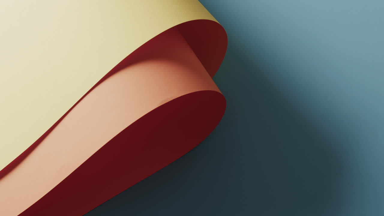 Close up of beige rolled piece of paper on blue background with copy space in slow motion