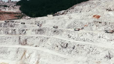 terraced quarry with trucks navigating excavation paths, captured in stunning aerial footage.