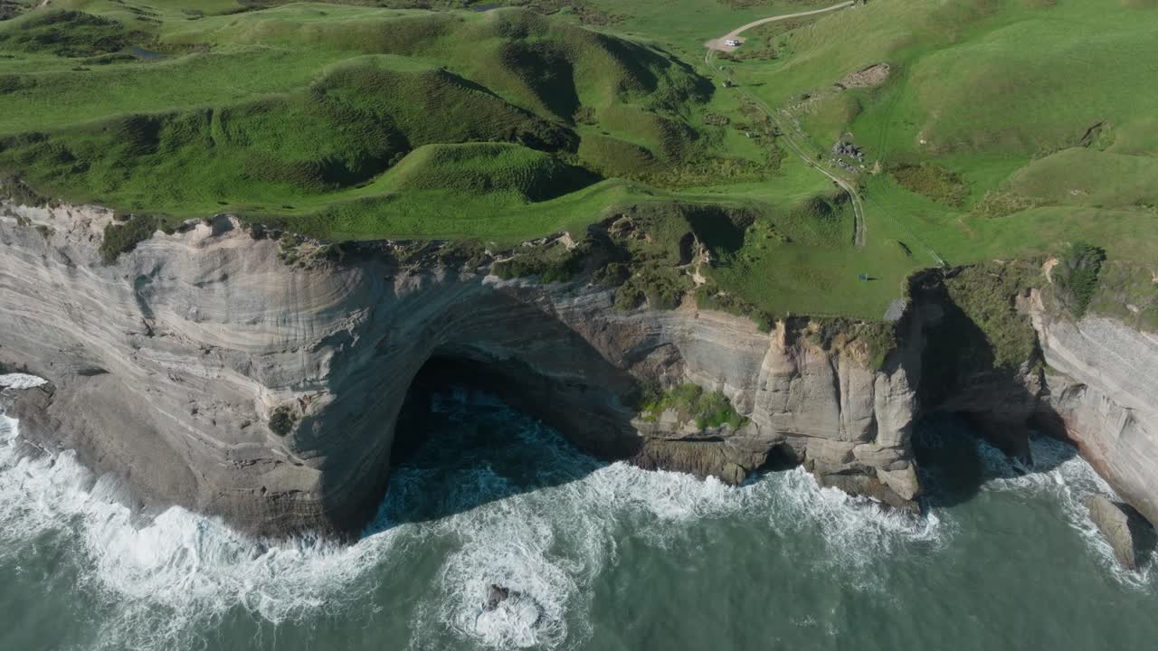 vista aérea de olas blancas y salvajes rompiendo contra los escarpados acantilados del cabo de despedida en el desierto remoto de la isla sur, nueva zelanda aotearoa