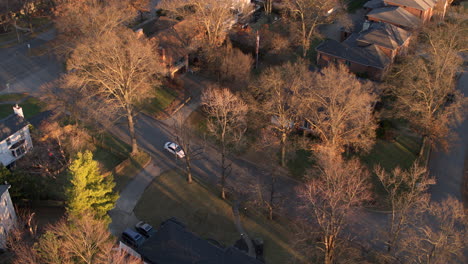 aerial flyover upscale homes and cars in a nice neighborhood at sunset