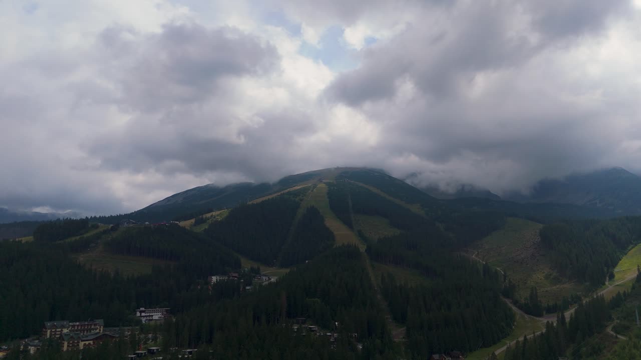 Aerial footage of Demanovska Dolina in Slovakia, showing Jasna ski resort, Vrbicke pleso lake, mountain peaks, and drifting clouds. Beautiful nature and travel visuals from the Zilina region
