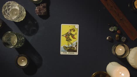 overhead shot of person giving tarot card reading laying down the fool card on table