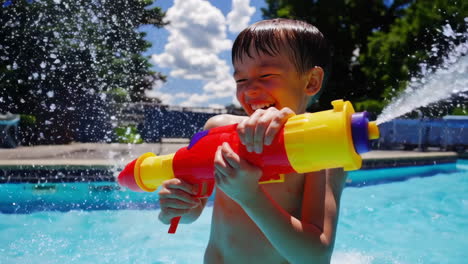 happy boy playing with water gun in swimming pool