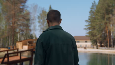 man walking in a forest by a lake