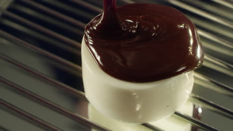 liquid chocolate spilling on panna cotta by hot icing at professional kitchen.