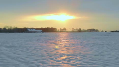 Sensacional-Vuelo-Aéreo-A-Baja-Altura-Sobre-Un-Vasto-Campo-Cubierto-De-Nieve-Blanca-Al-Atardecer