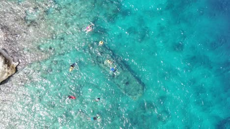 snorkelers in clear blue waters at tugboat beach, curacao, aerial view