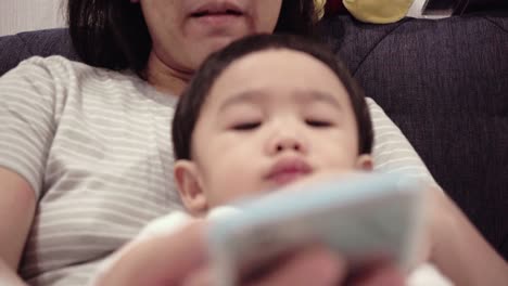 asian baby using smartphones with mom on the bed