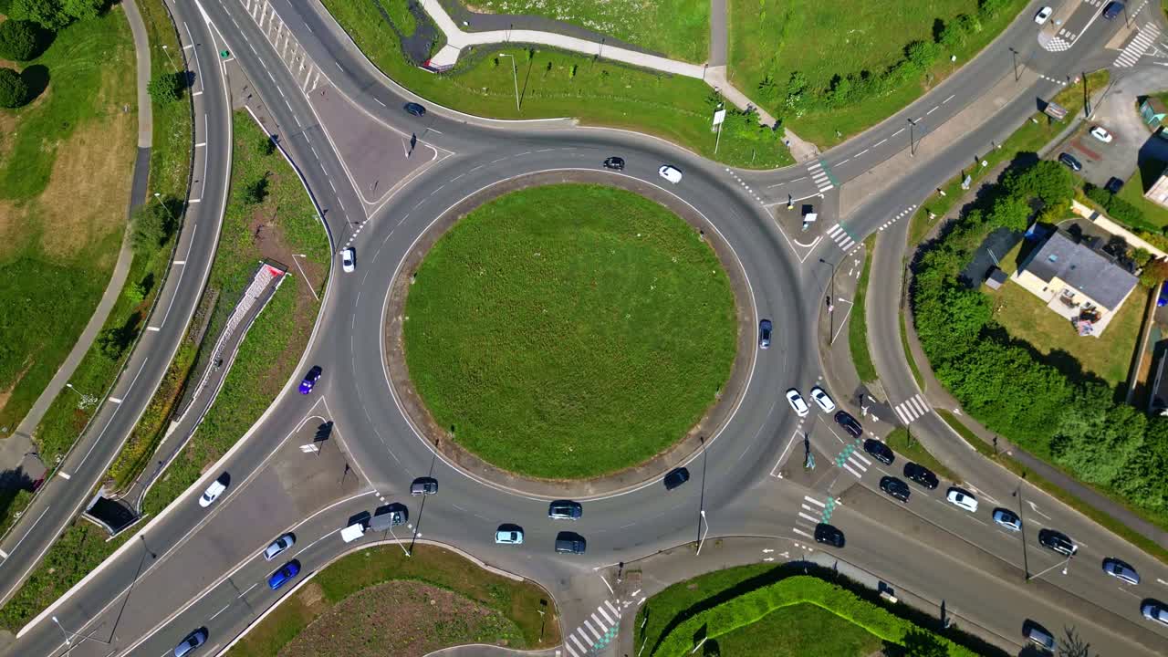 Top-down perspective drone view of large multi-lane roundabout with heavy traffic motion, Laval, Mayenne, France.