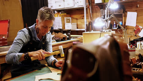 attentive craftswoman nailing leather