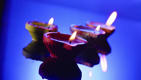 Close-up-of-burning-candles-in-row-celebrating-diwali-on-blue-background