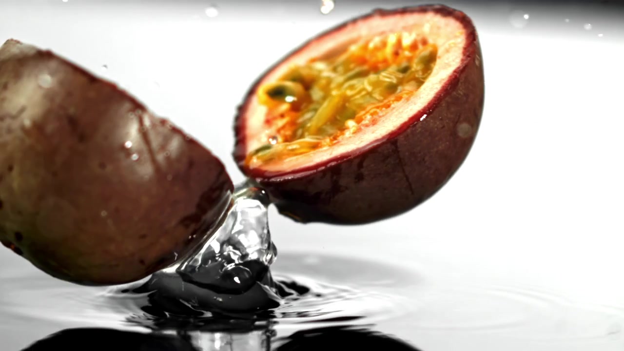 Slowmotion af frisk passionsfrugt, der deler sig på vandoverfladen