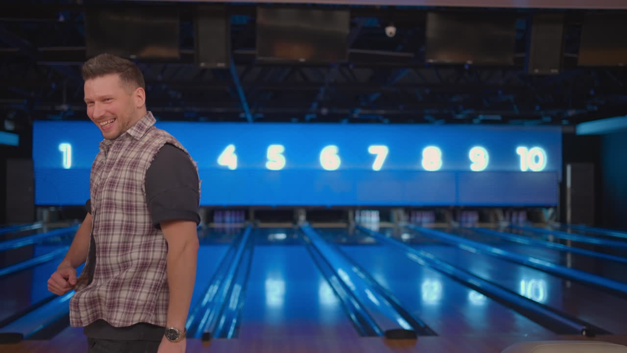 Portrait Caucasian man jumps joyfully looking into the camera celebrate the victory in slow motion. Throw in the bowling alley to make a shoot. Victory dance and jump with happiness.