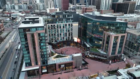 aerial pullback from mcgregor square in downtown denver colorado and slowly revealing skyline buildings and city roads with cars crossing each other