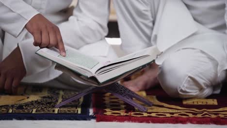 closeup of indian muslim men reading quran holy book