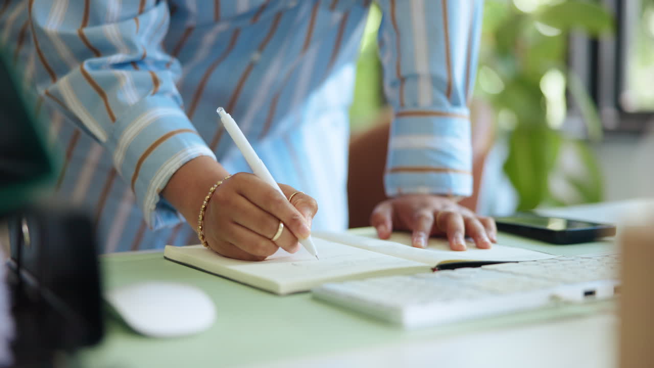 Close Up of Person's Hand Writing in Notebook on Desk