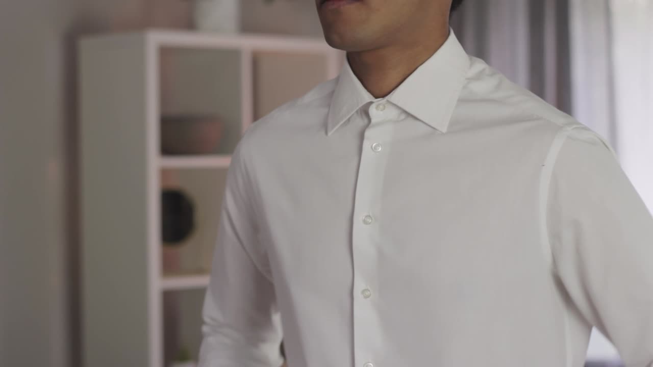 застегивает рукава белой рубашки, молодой азиатский бизнесмен, чистый взгляд