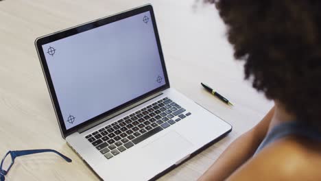 Video-of-biracial-woman-working-with-laptop-with-copy-space-on-screen