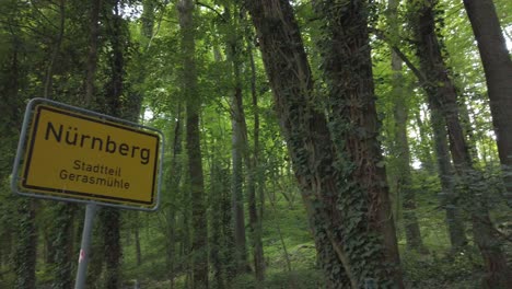 Camera-tilting-and-panning-from-the-forest-with-sun-shing-trough-down-to-the-town-sign-of-bavarian-franconian-town-Nuremberg