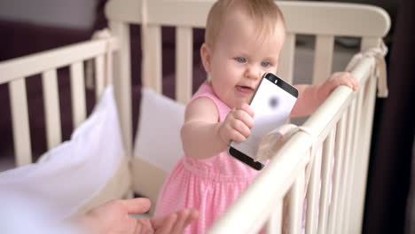 cute baby in crib touch smartphone. baby technology concept