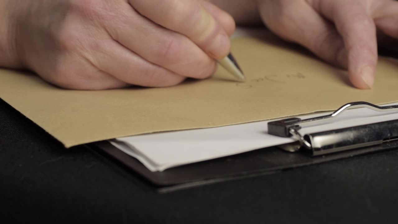Busy person writing up address on envelope on a clipboard close up