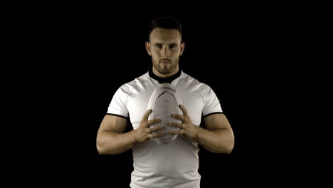 serious rugby player holds rugby ball