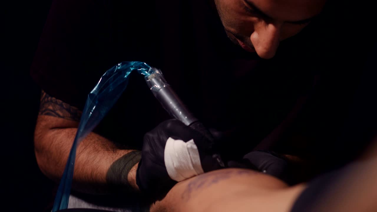 Skilled tattoo master tattooing design with ink on client's leg