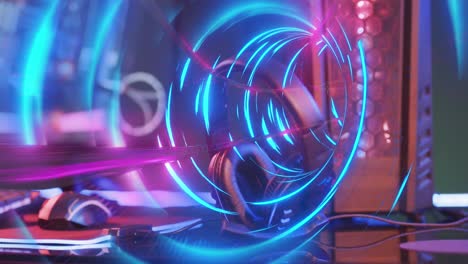 Animation-of-neon-light-trails-over-video-game-computer-equipment