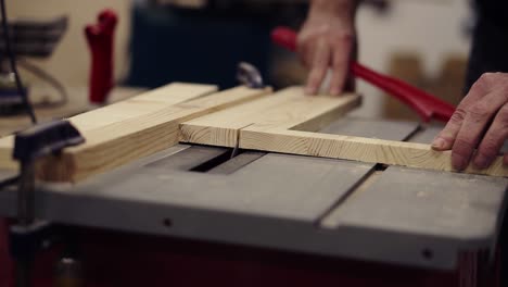 Front-view-footage-of-cutting-wooden-board-on-saw-machine.-Action.-Industrial-machine-with-circular-saw-cuts-wooden-board.-Male-hands-gently-pushing-a-pattern-to-a-circular-disk