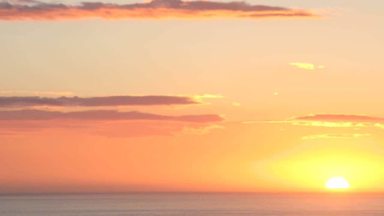 생생한 주황색 구름은 태양이 수평선 아래로 미끄러짐에 따라 검게 어두워집니다.