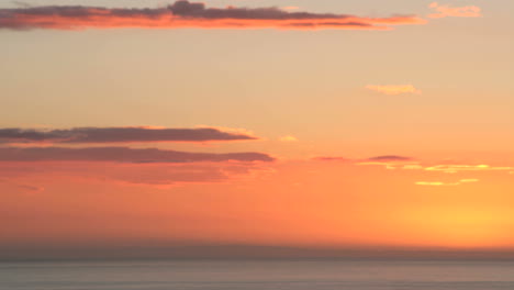 Leuchtend-Orangefarbene-Wolken-Verdunkeln-Sich-Zu-Schwarz,-Wenn-Die-Sonne-Unter-Den-Horizont-Rutscht