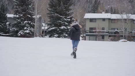 back view of teenage girl running in snow, slow motion