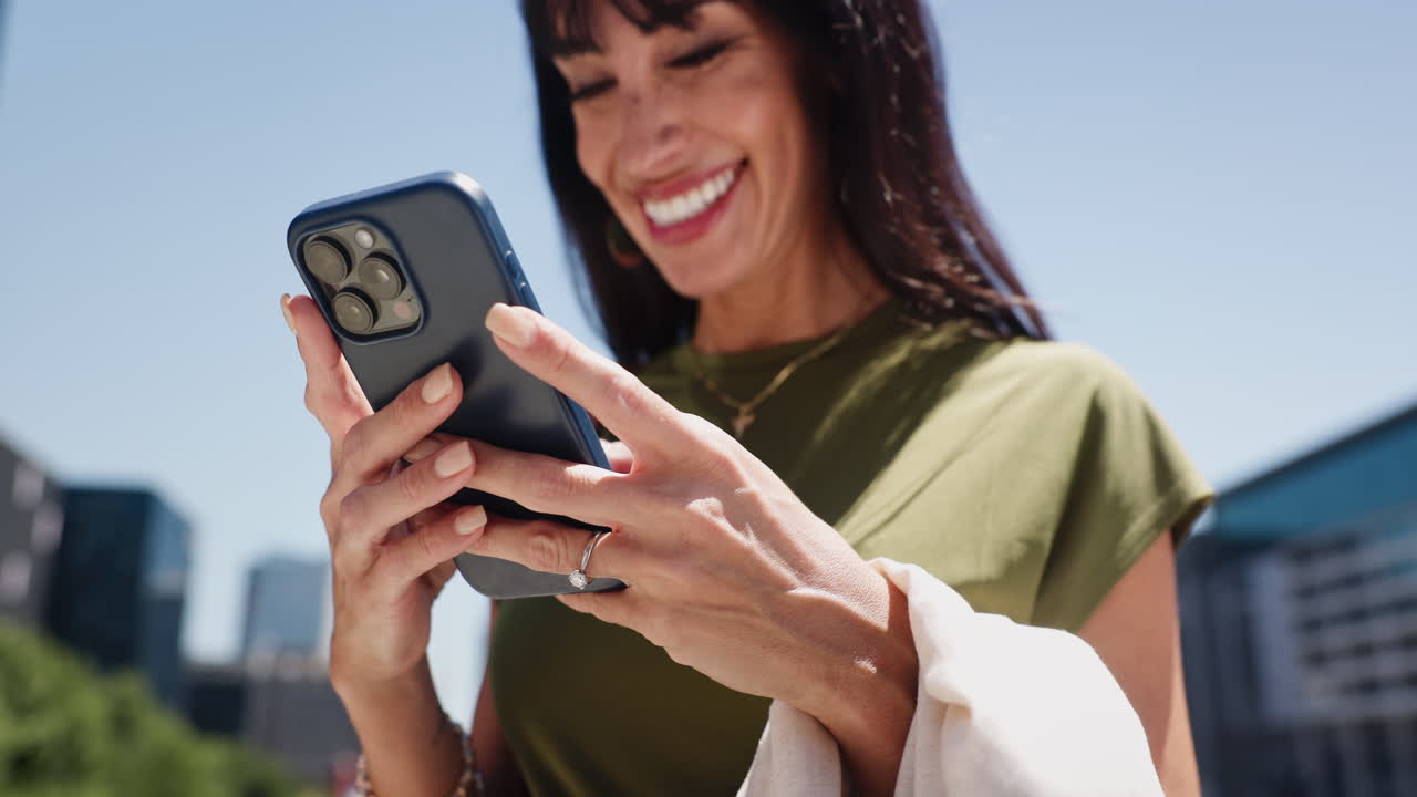 Donna felice che sorride mentre usa lo smartphone all'aperto