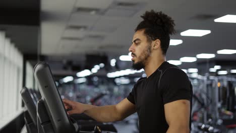 fitness man starting his training cardio exercise on running machine in gym