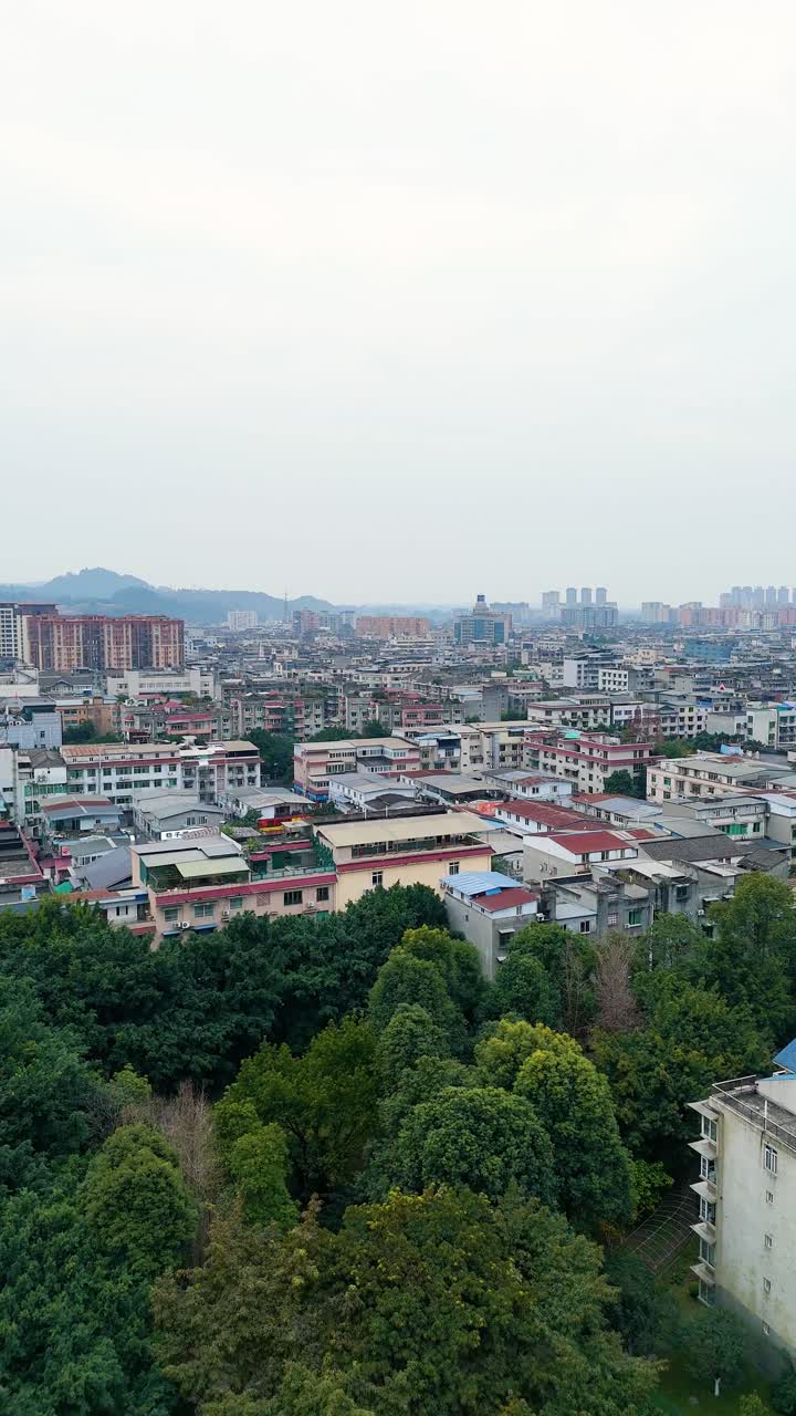 Vertical aerial view of Chengdu's Xinjin County showcases a dense urban cityscape with residential buildings, bustling streets, and surrounding urban development. China