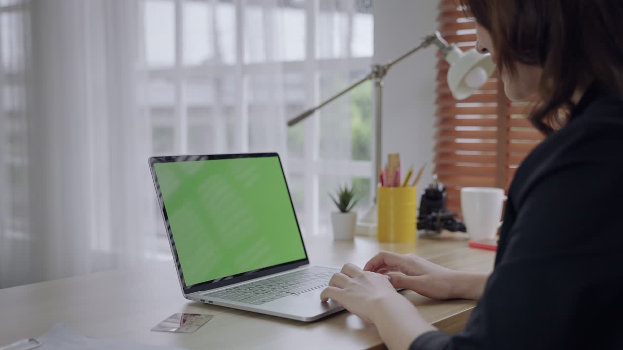 imágenes de pantalla verde de una computadora portátil con una mujer asiática sentada con la espalda.