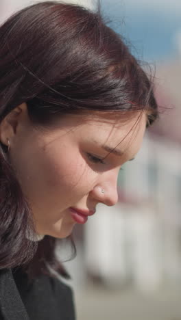 dama sentada pensativa, iluminada por la luz del sol, el cabello balanceándose suavemente en el viento con una luz suave que destaca sus rasgos, el fondo borroso con un suave efecto bokeh