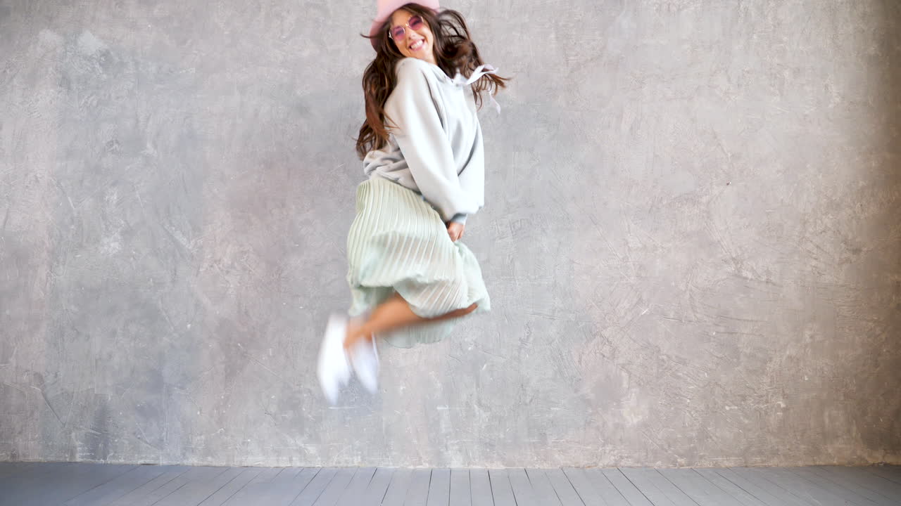 mujer feliz bailando frente a una pared gris