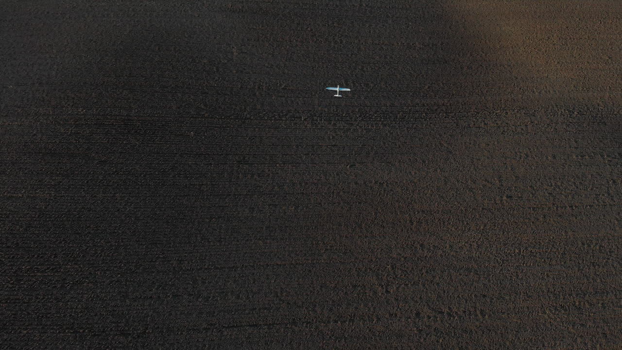 갈색 들판 위를 날고 있는 흰색 무선 조종기