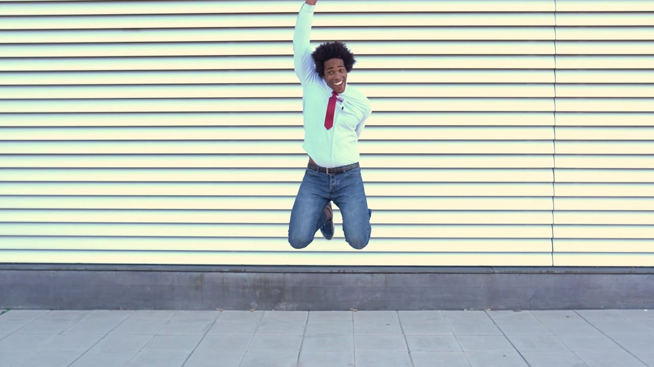 Uomo d'affari afroamericano che salta all'aperto, con capelli afro