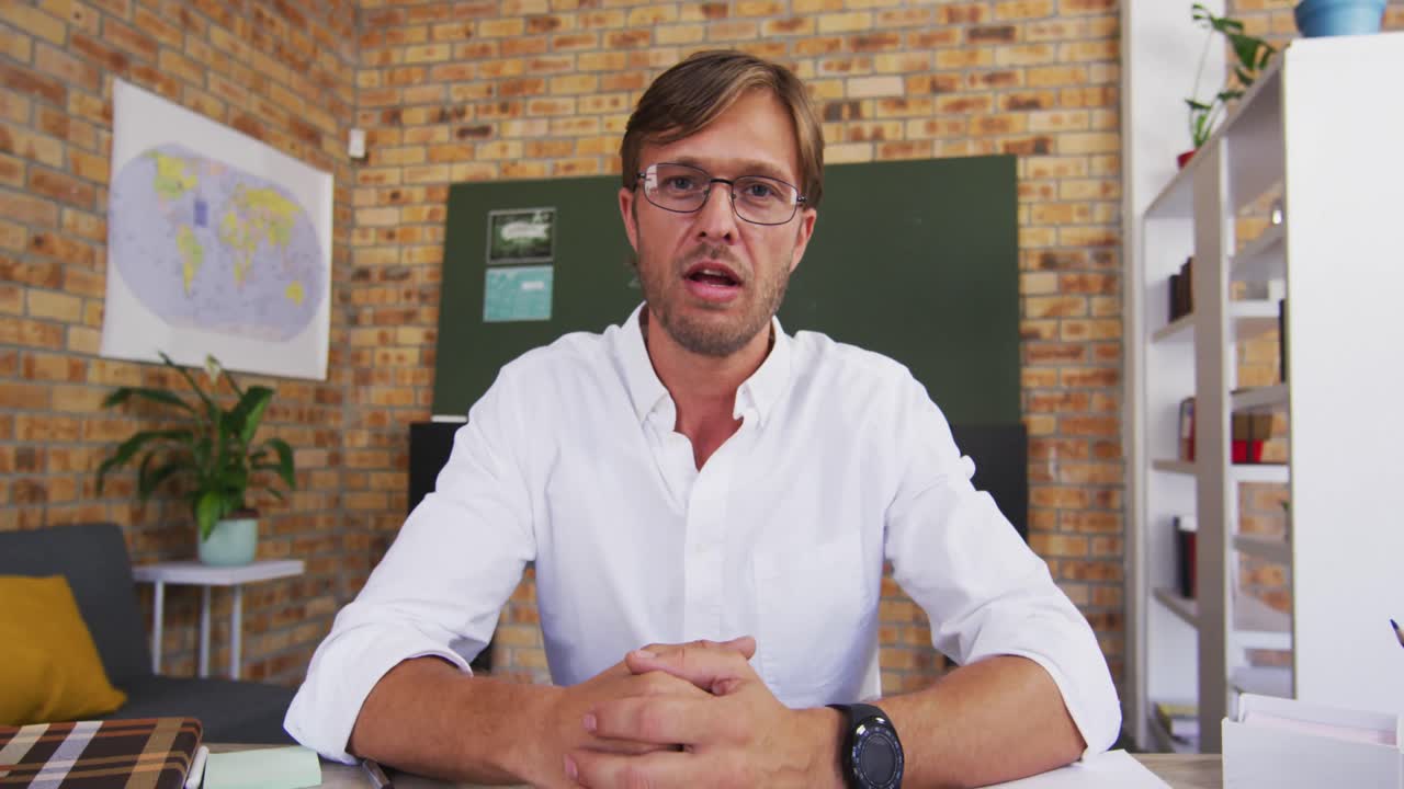 Ritratto di un professore caucasico che insegna in videochiamata in classe a scuola.