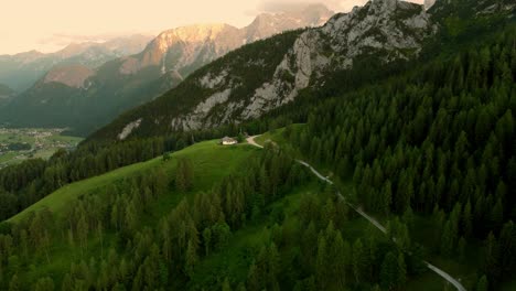 Pequeña-Cabaña-En-Una-Cornisa-Frente-A-Un-Enorme-Acantilado-Durante-La-Puesta-De-Sol-En-Los-Alpes-De-Lofer,-Austria