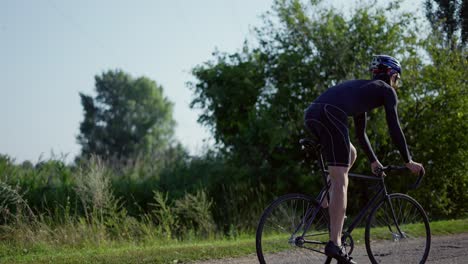 fahrradfahrer mit helm beginnt seine fahrt entlang der leeren straße entlang der landschaft