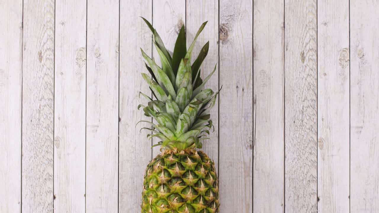 Fresh organic pineapple rolling in place on wooden theme. Stop motion