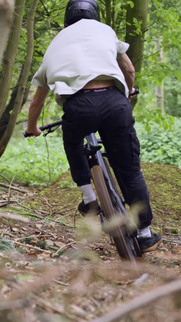 Vertical Video Of Man On Mountain Bike Making Mid Air Jump On Dirt Trail Through Woodland 