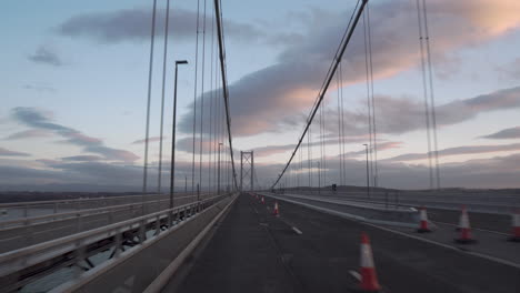 Toma-En-Movimiento-De-Un-Vehículo-Que-Cruza-Un-Puente-De-Carretera-Con-Una-Maravillosa-Luz-De-Puesta-De-Sol-Y-Nubes-En-Edimburgo,-Escocia