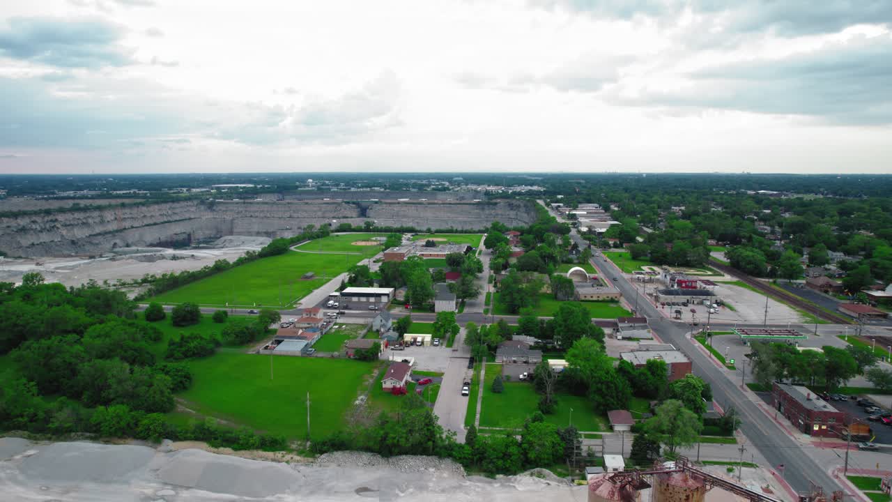 Aerial view of Thornton, Illinois, showcasing a small town with a large quarry in the background under a cloudy sky.