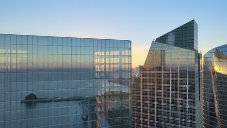 filmische langsame luftschwenkung an der spitze moderner wolkenkratzer-bürogebäude mit durchscheinenden und reflektierenden glasfenstern bei sonnenuntergang, goldene stunden, nahaufnahme, innenstadt von buenos aires, argentinien