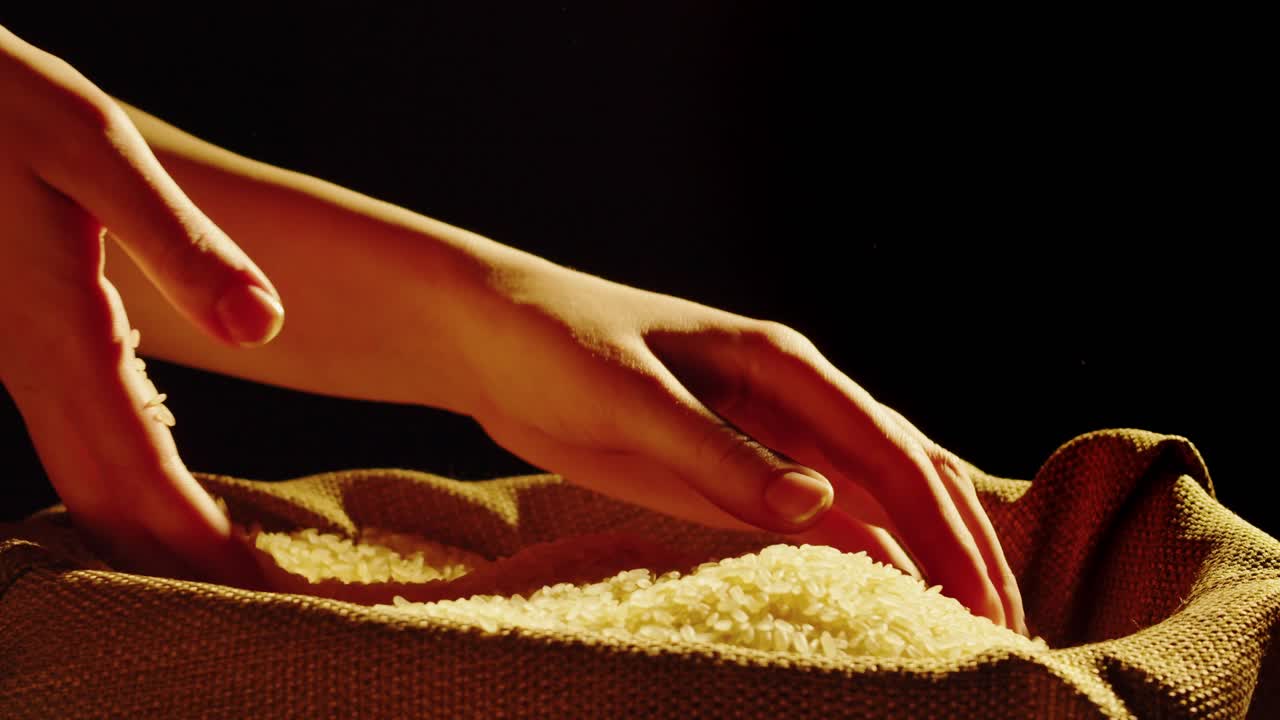 Hands sifting and pouring rice grains into a burlap sack